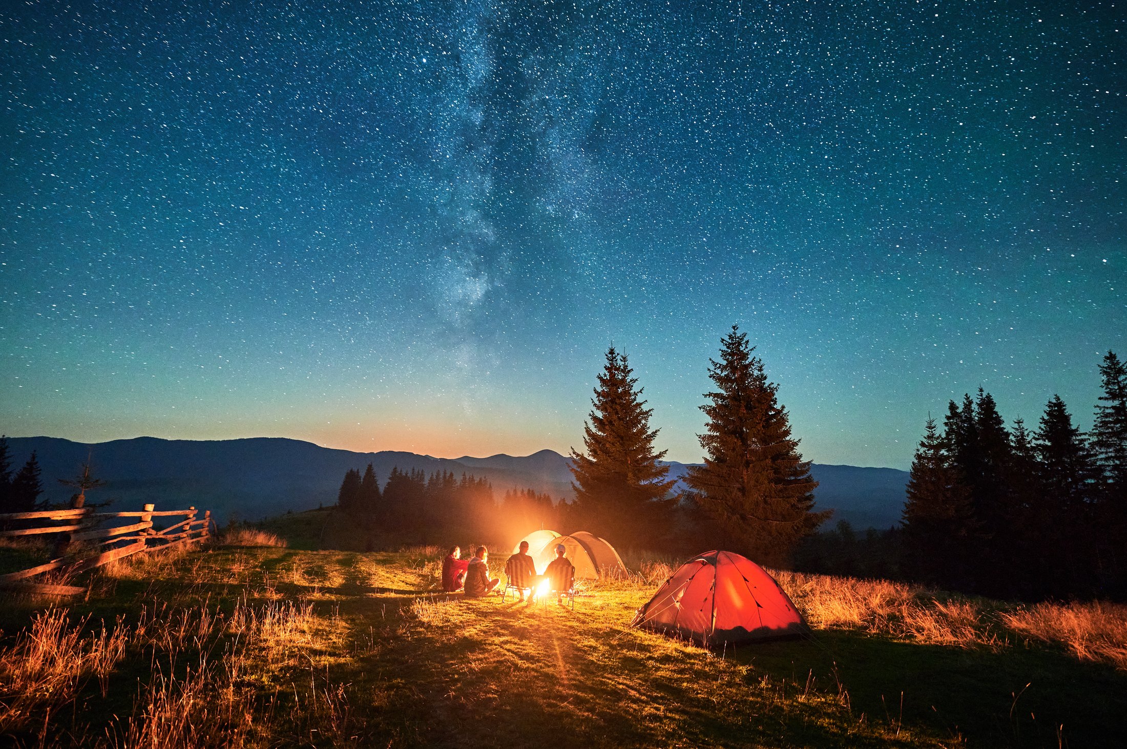A campsite with tents under a starry mountain sky