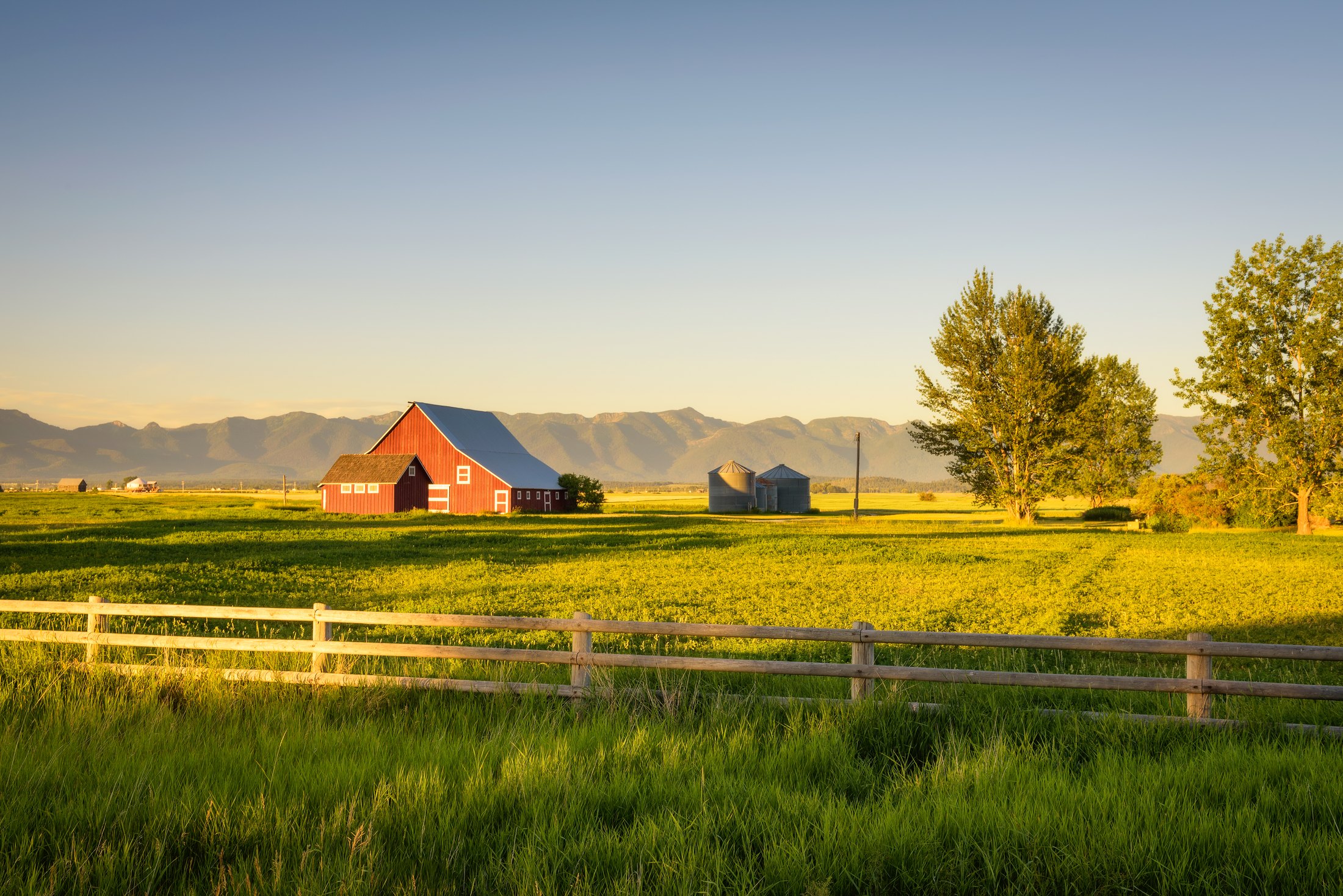A red barn and farmhouse in the countryside at golden hour